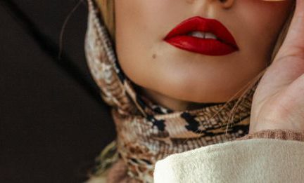 Lipstick Shades - Low angle of gorgeous young lady with red lips in elegant outfit adjusting trendy sunglasses while standing on street with umbrella